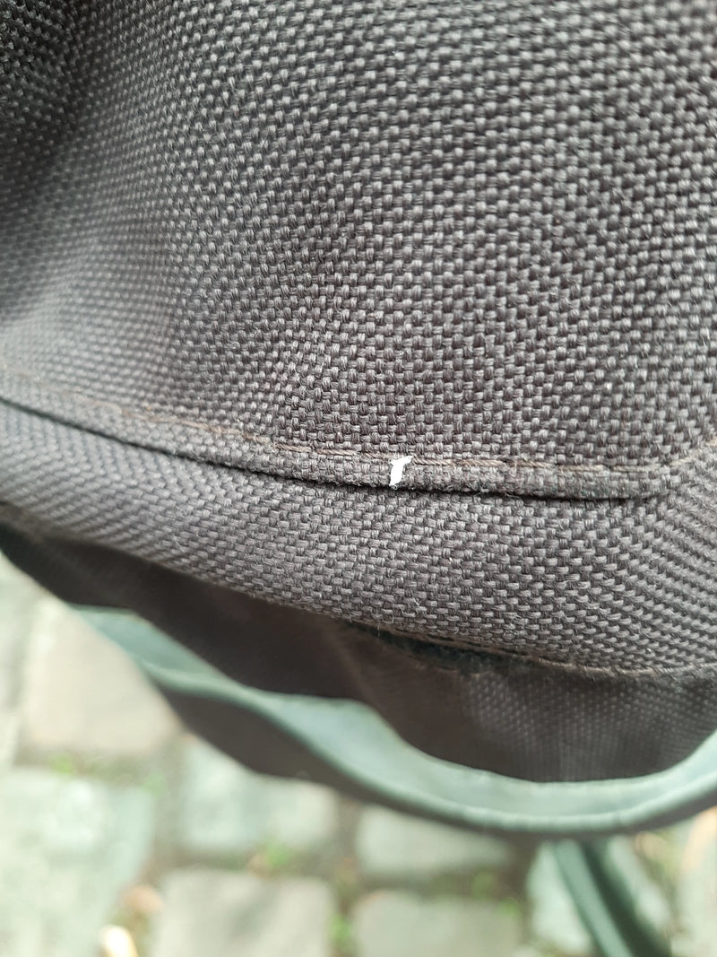 Een netwants is zichtbaar op een donkere textielstof. Het kleine insect zit rustig op het materiaaloppervlak.